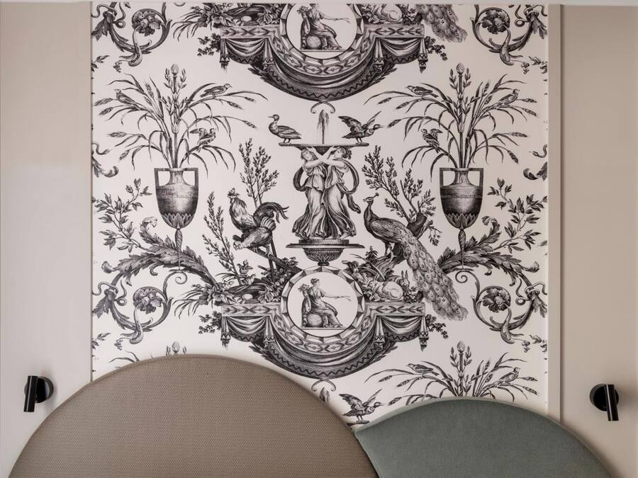 A room with a large, ornate tapestry featuring botanical and mythological motifs.