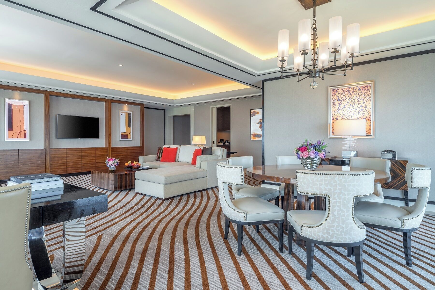 A modern living room with a sofa, chairs, a dining table, and a TV.