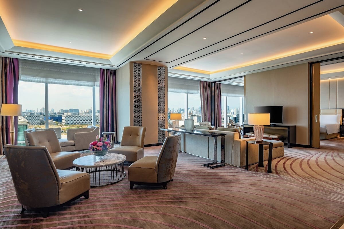 Une chambre d’hôtel moderne avec vue sur la ville, un coin salon avec une table ronde et un téléviseur.