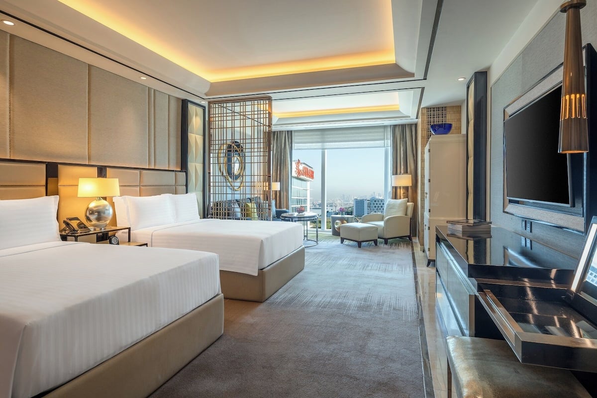 Une chambre d’hôtel avec deux lits, une télévision, un minibar et une vue sur le paysage urbain.