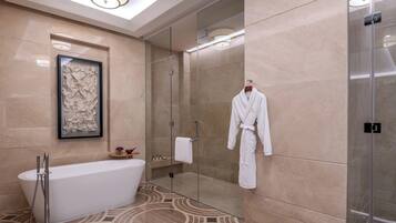 Un baño moderno con una bañera independiente, cabina de ducha con paredes de vidrio y una obra de arte abstracta enmarcada en la pared.