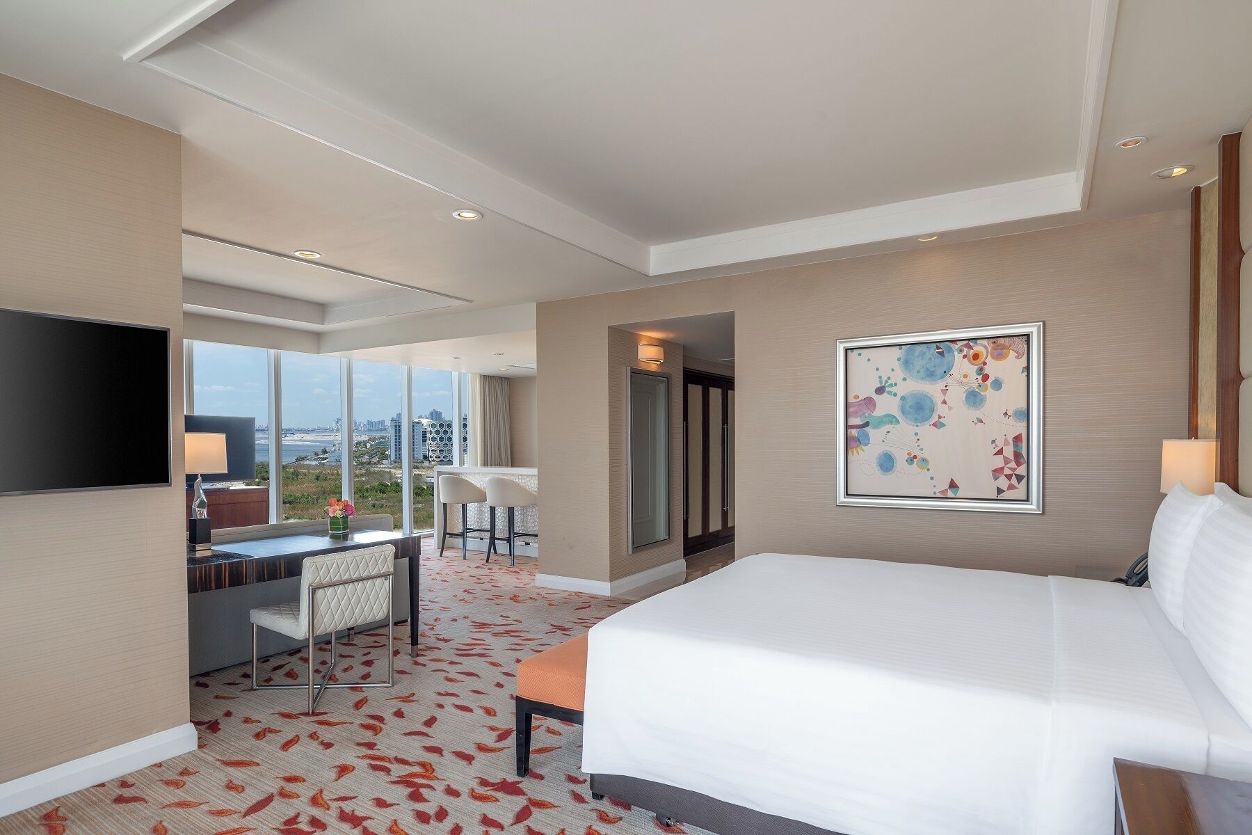 Une chambre d’hôtel avec un grand lit, un bureau avec une chaise, une télévision et un tableau au mur.