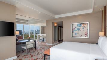 Une chambre d’hôtel avec un grand lit, un bureau avec une chaise, une télévision et un tableau au mur.