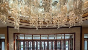 A spacious lobby with a modern chandelier and large glass doors leading outside.