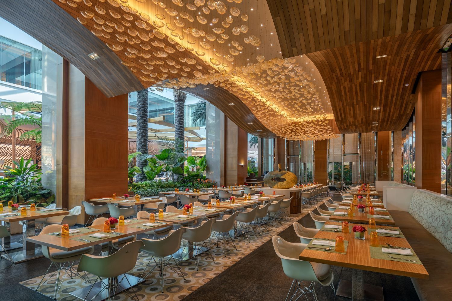 Un restaurante espacioso con techos altos, mobiliario moderno y vistas al exterior.