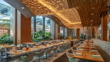 A spacious restaurant with high ceilings, modern furniture, and a view of the outdoors.