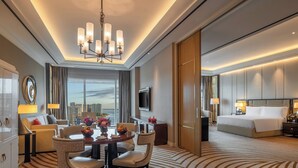A hotel room with a dining area, a bed, a TV, and a city view.