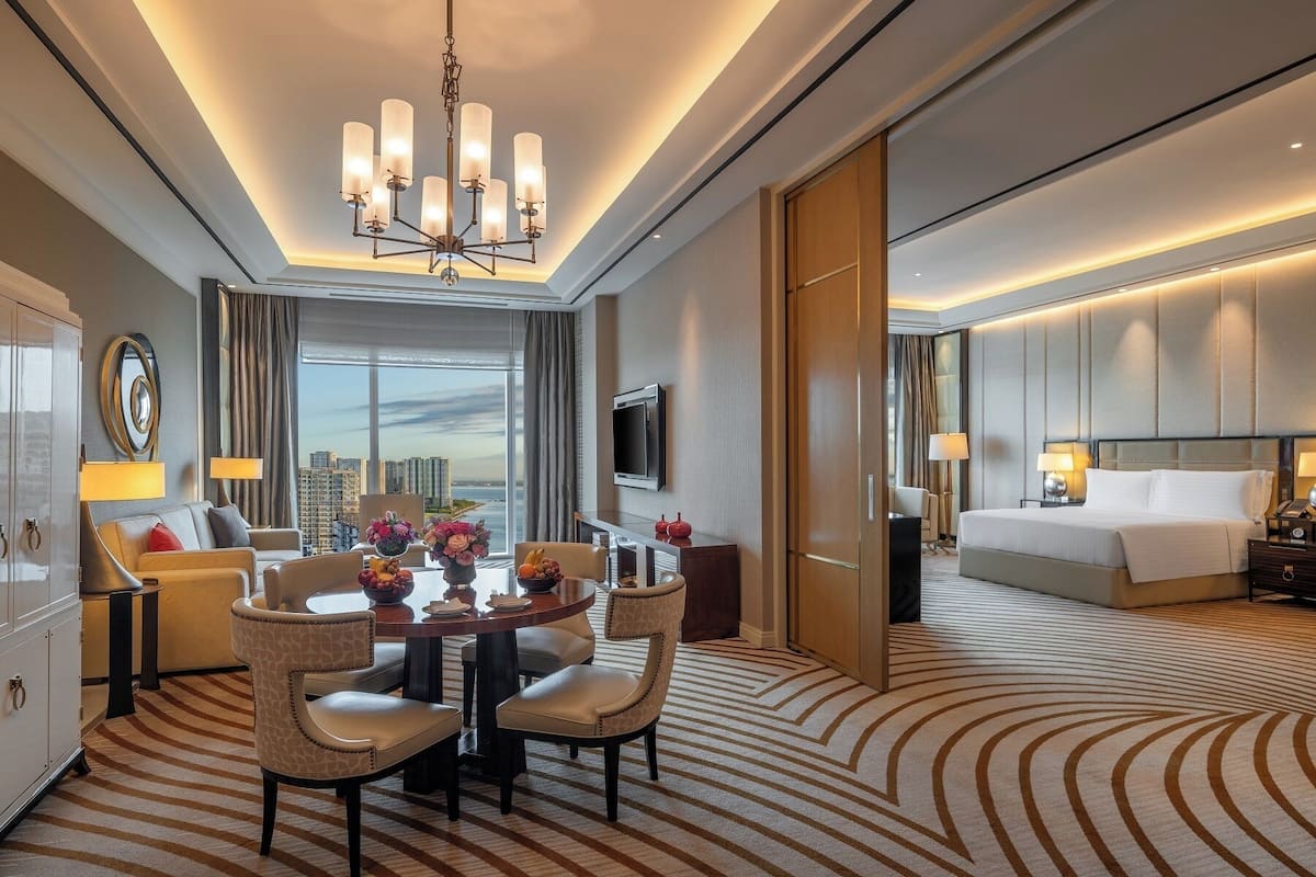 Une chambre d’hôtel comprenant un coin repas, un lit, une télévision et donnant sur la ville.