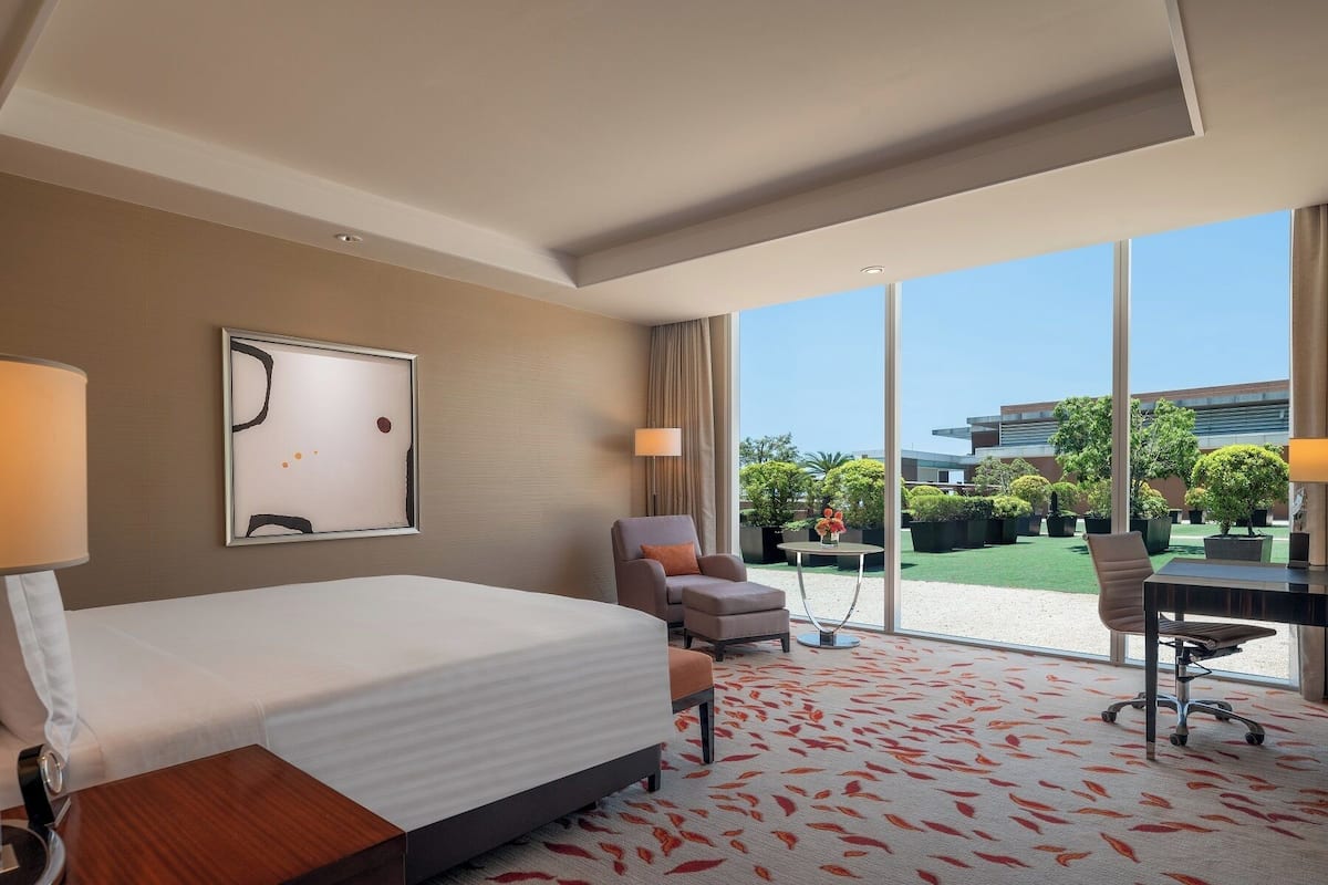 Une chambre d’hôtel avec un lit, un bureau, une chaise et une vue sur l’extérieur.