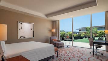 A hotel room with a bed, a desk, a chair, and a view of the outdoors.