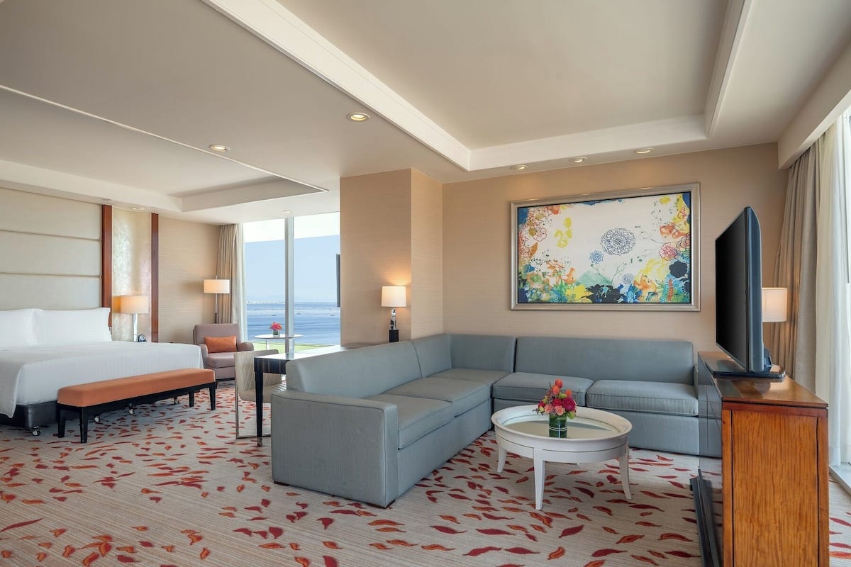 Une chambre d’hôtel avec un lit, un canapé, une table basse et un téléviseur.