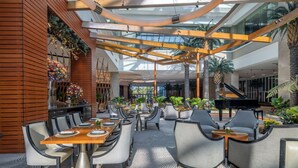 A spacious indoor area with a high ceiling, modern furniture, and a grand piano.