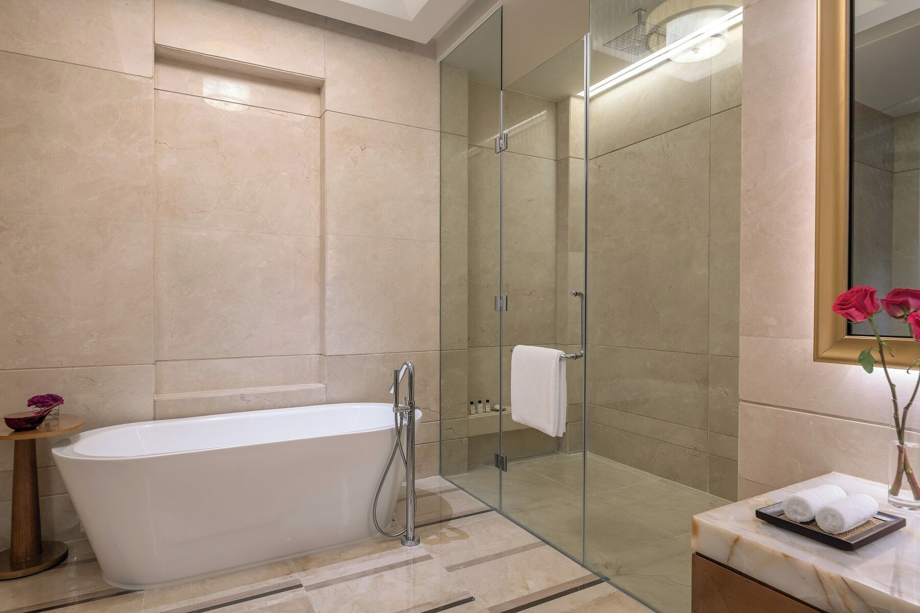 Un baño moderno con una bañera independiente, ducha con mampara de cristal y tocador con espejo.