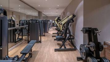 Un gimnasio con diversos equipos de ejercicio, bancos y espejos en las paredes.