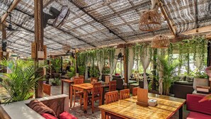 Un espace intérieur aménagé avec des meubles en bois, un toit de chaume et des plantes suspendues.