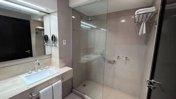 A modern bathroom with a glass-enclosed shower, a sink with a mirror, and a towel rack.