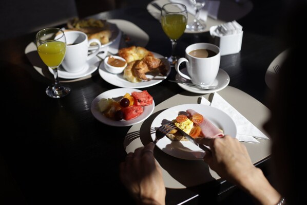 Una mesa de comedor con platos de comida, una taza de café y un vaso de jugo.