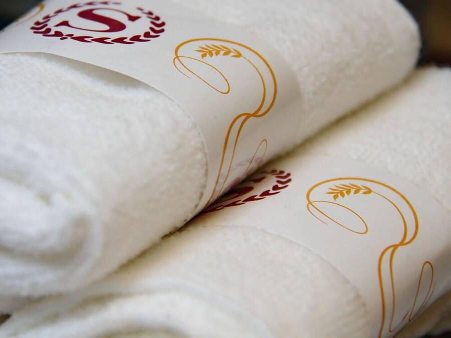 A stack of white towels with gold embroidery.
