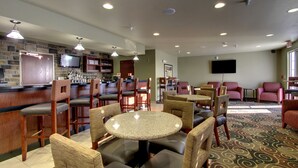 A hotel lobby with a bar area, seating arrangements, and a television screen. - Cobblestone Inn & Suites - Bottineau (Bottineau)