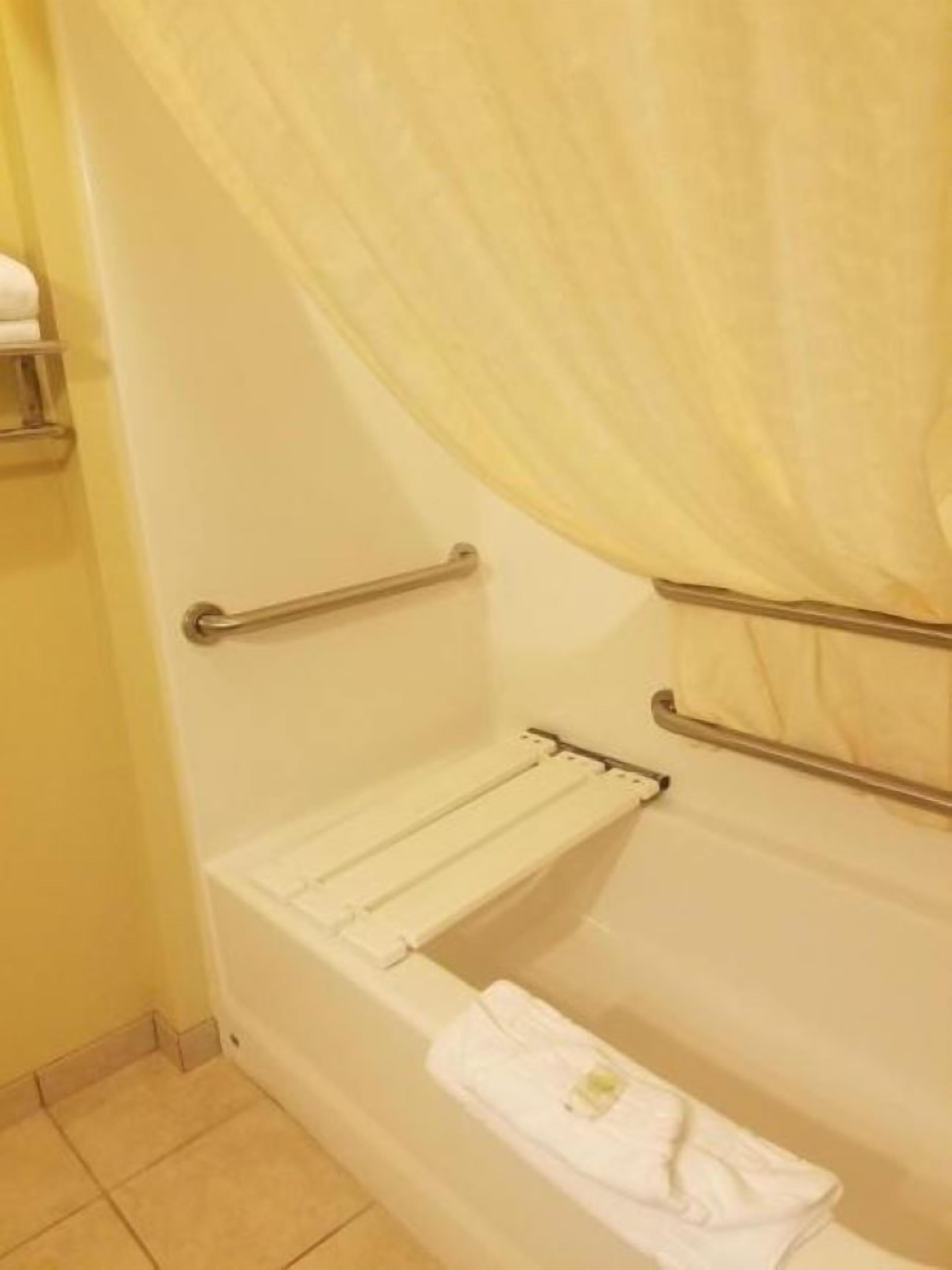 A bathroom with a bathtub, a towel rack, and a shower curtain.