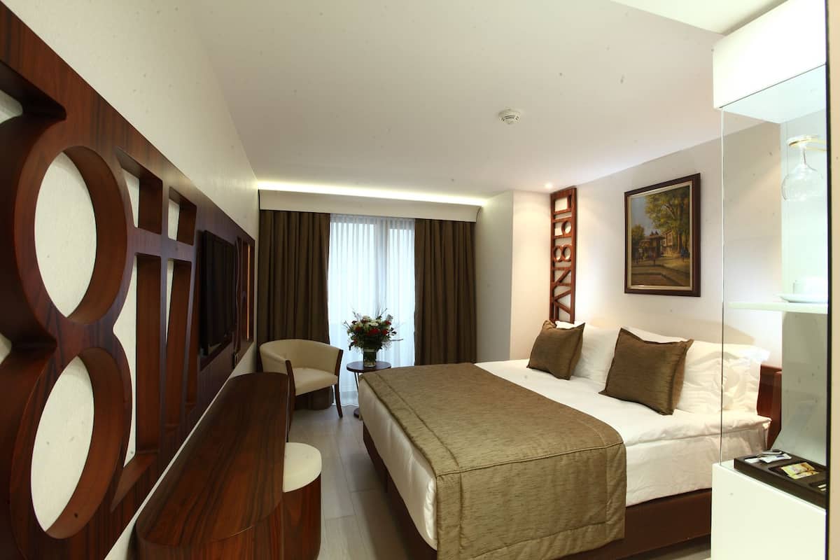 Une chambre d’hôtel avec un grand lit, un bureau, une chaise et un tableau au mur.