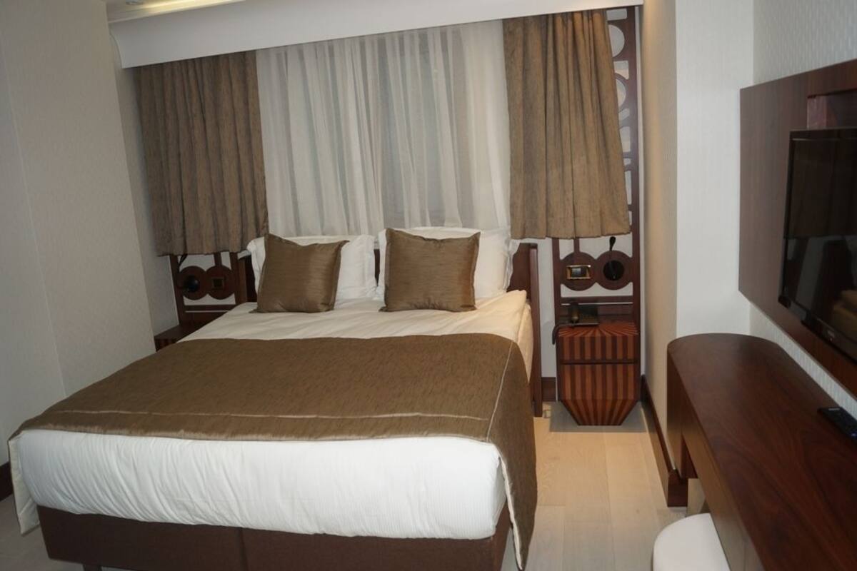Une chambre d’hôtel avec un grand lit, une télévision et une table de chevet en bois.