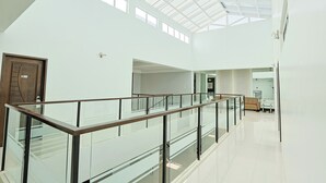 A spacious, modern interior with a glass railing, high ceilings, and natural light from skylights. - Holiday Suites Business District (Empire Suites Hotel) (Puerto Princesa)