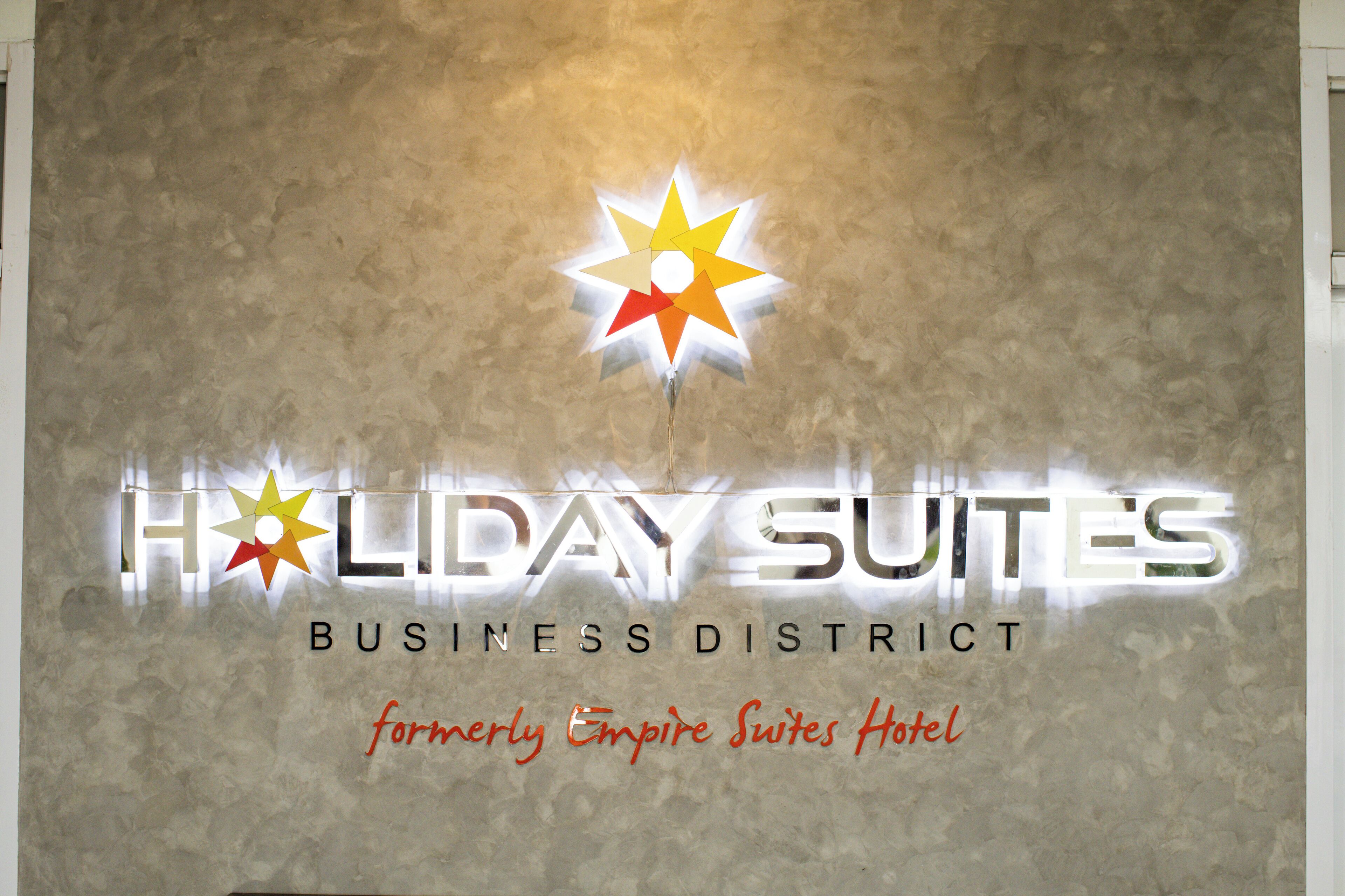 A sign for Holiday Suites Business District, formerly Empire Suites Hotel.