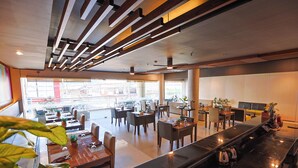 A modern restaurant with a long counter, multiple tables, and chairs. - Holiday Suites Business District (Empire Suites Hotel) (Puerto Princesa)