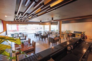 Un restaurante moderno con una barra larga, varias mesas y sillas.