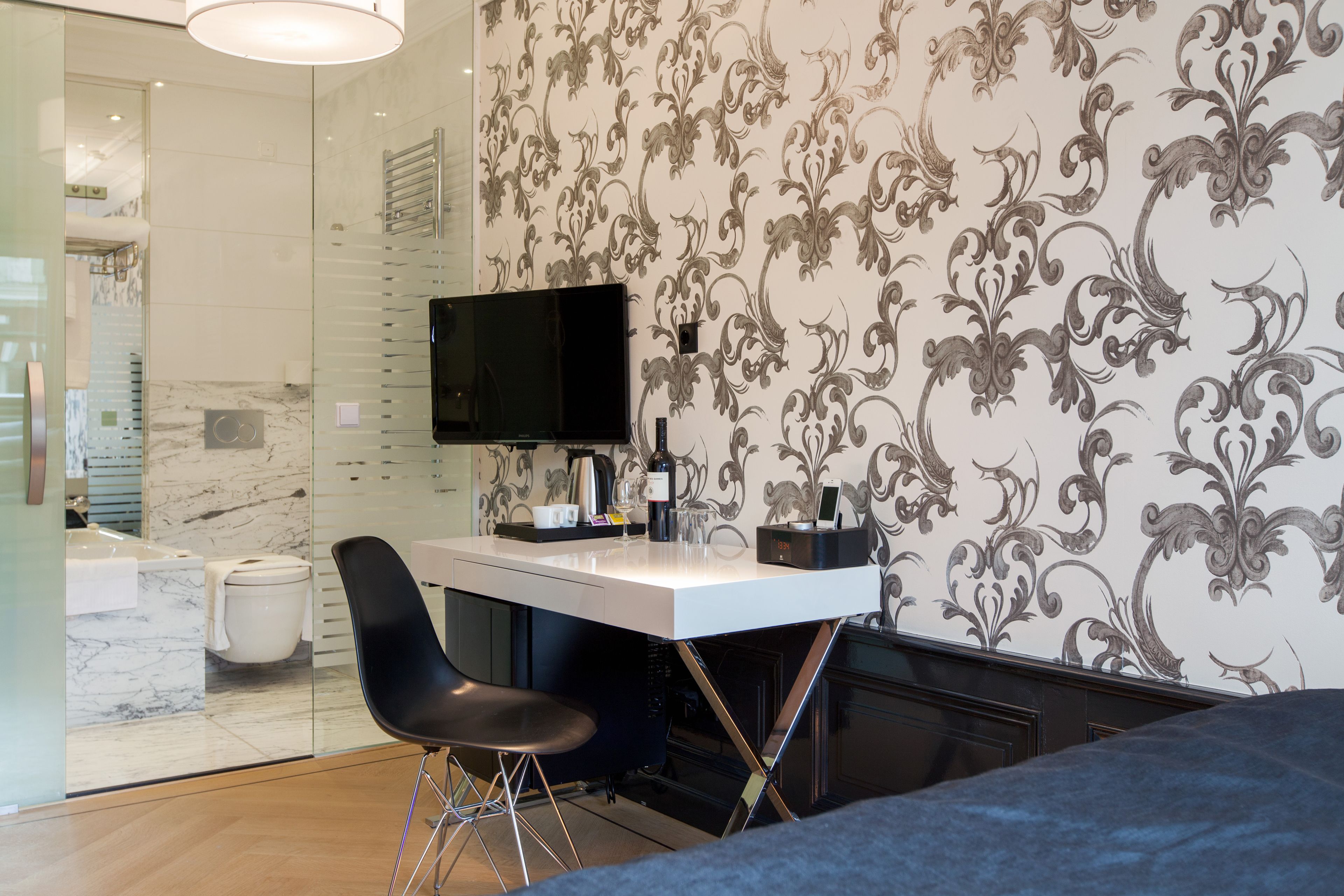A modern bathroom with a glass shower enclosure, a white sink, and a black chair.
