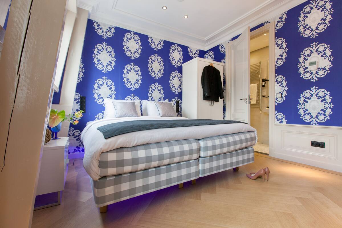 Une chambre à coucher avec un lit, une armoire et une salle de bain visible à travers une porte ouverte.