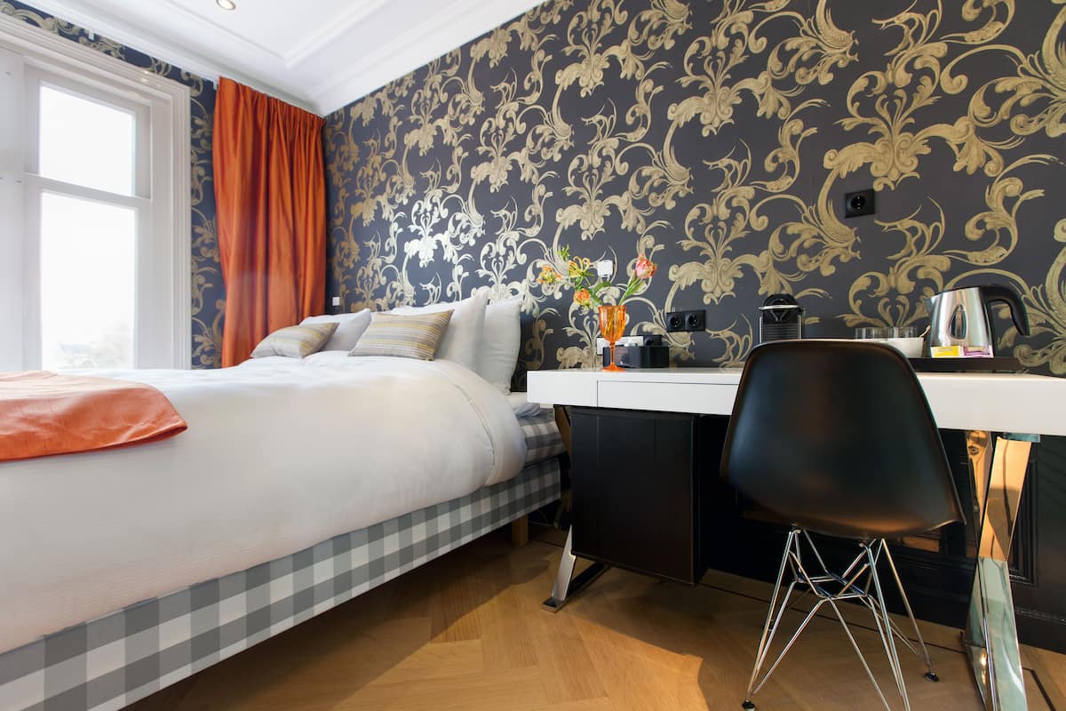 Une chambre d’hôtel avec un lit, un bureau et une chaise.