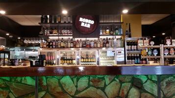 A bar with a 'RODEO BAR' sign, shelves of liquor bottles, and a stone wall in the foreground.