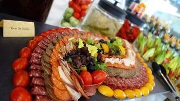 A charcuterie board with various meats, cheeses, and vegetables.