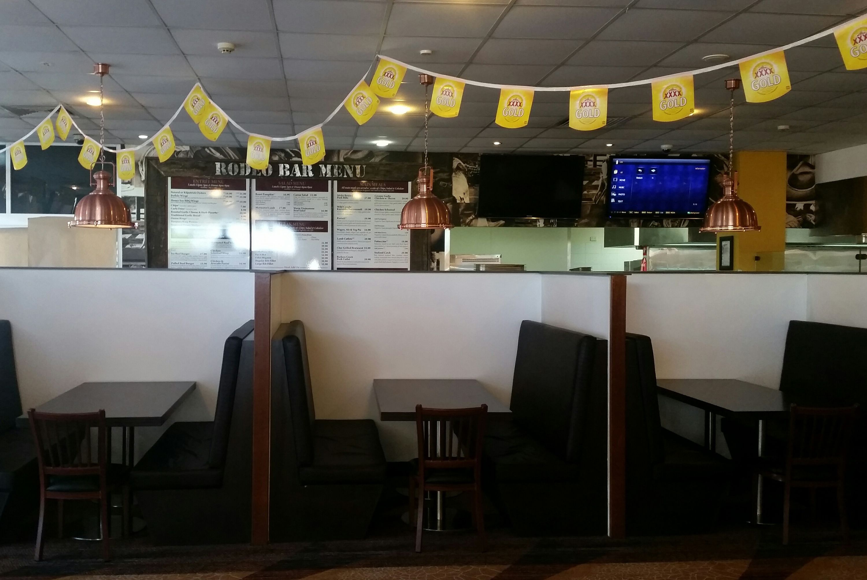 Interior de restaurante con cabinas, una pizarra de menú y pancartas amarillas.