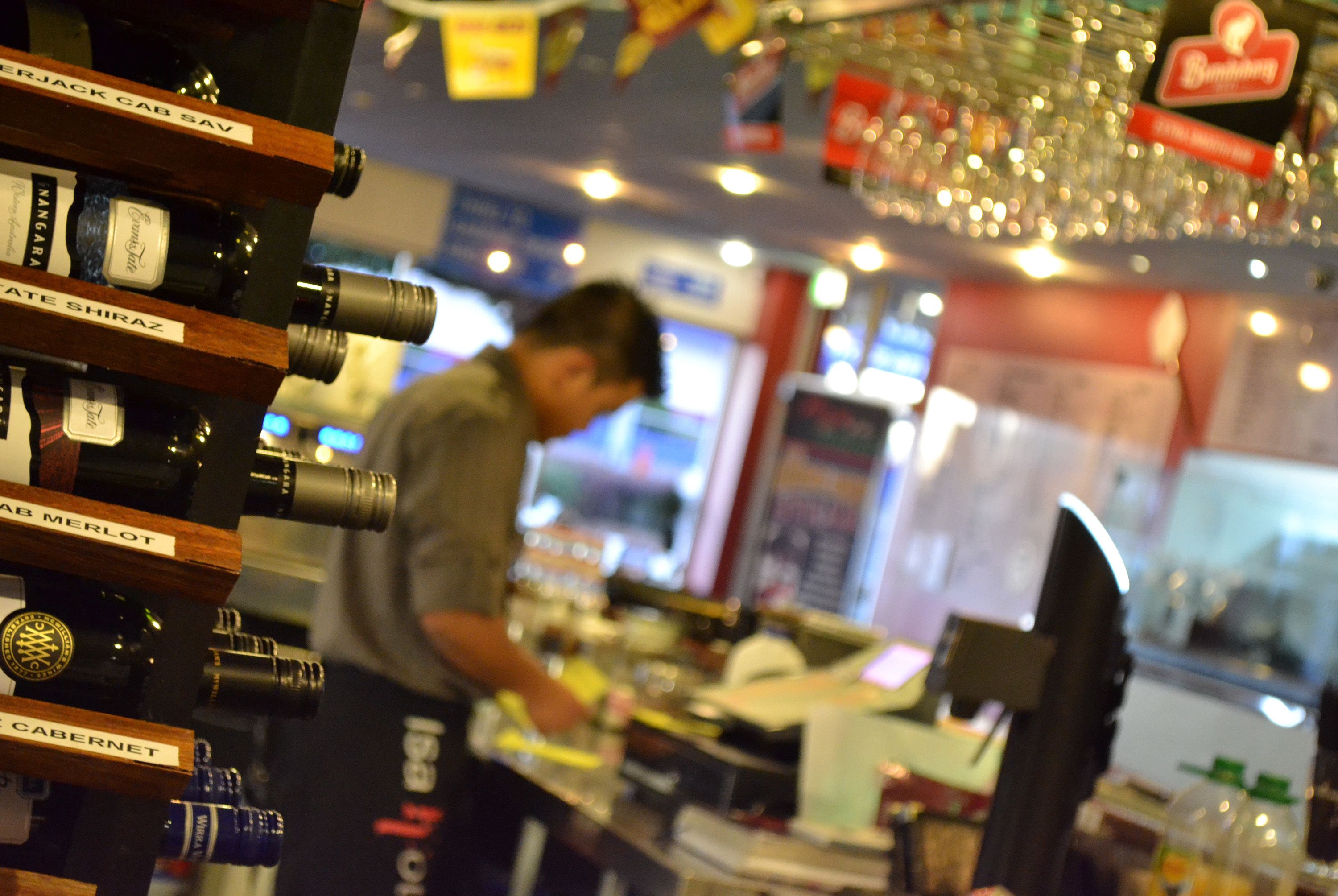 A wine rack with various bottles and a person working at a counter.