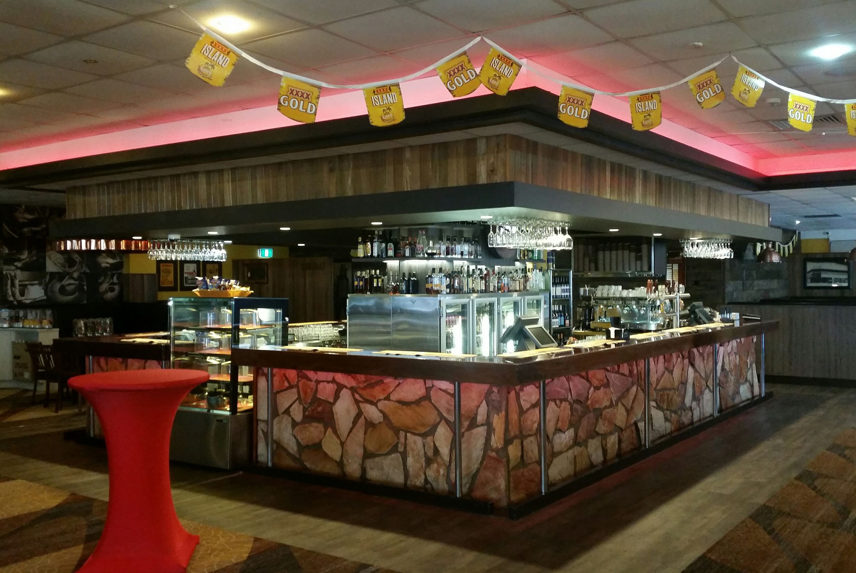 A bar area with a stone counter, glass display cases, and a red table.
