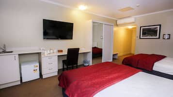 A hotel room with a bed, a desk, a chair, a TV, and a wardrobe.