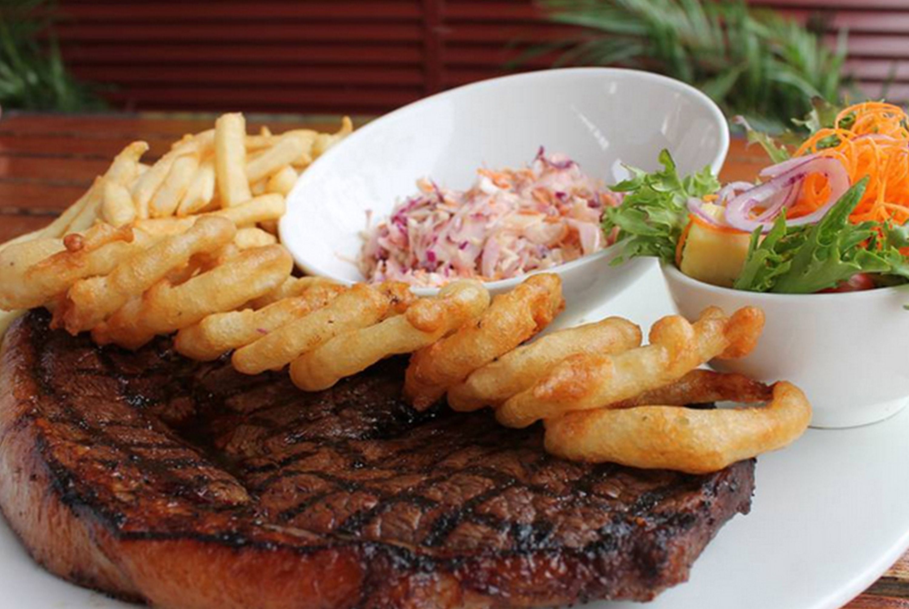 A steak with fries and a side salad on a plate.