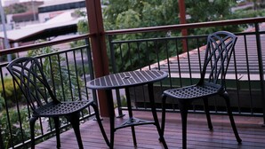 A balcony with two metal chairs and a small table, surrounded by a metal railing. - Redearth Hotel (Mount Isa City)