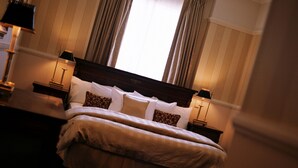 A neatly made bed with a wooden headboard, two bedside tables with lamps, and a window with curtains. - Redearth Hotel (Mount Isa City)