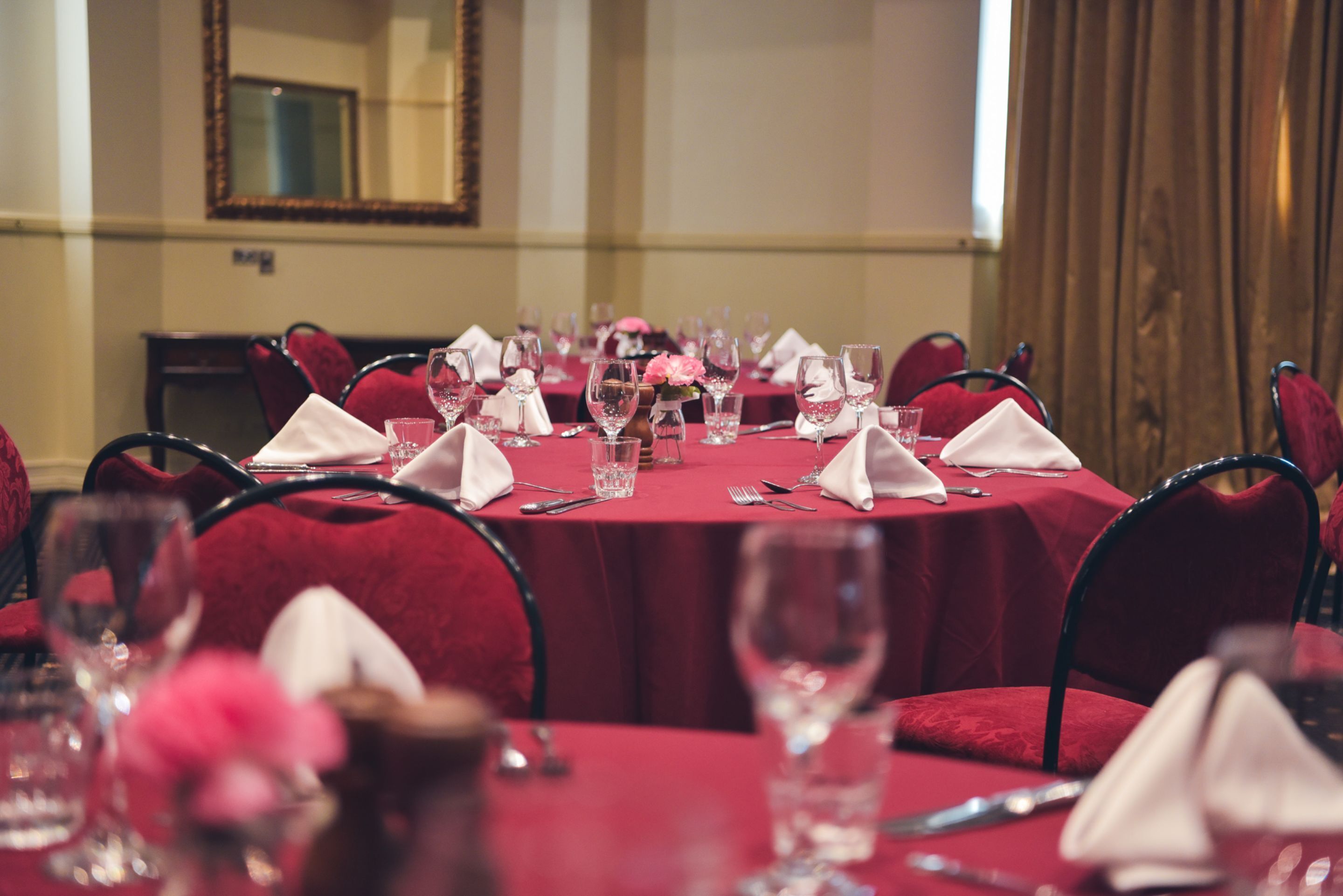 A conference room with round tables, red tablecloths, and matching red chairs.