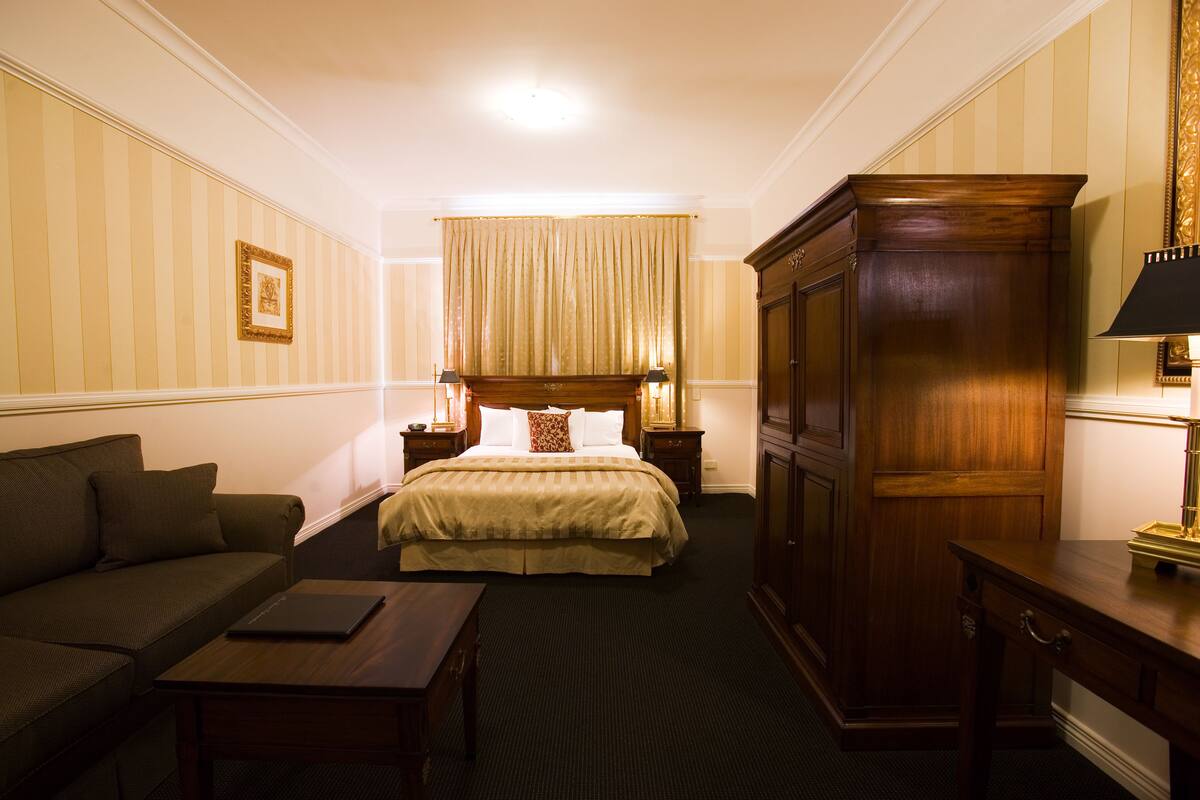 Una habitación de hotel con cama, sofá, escritorio y armario.