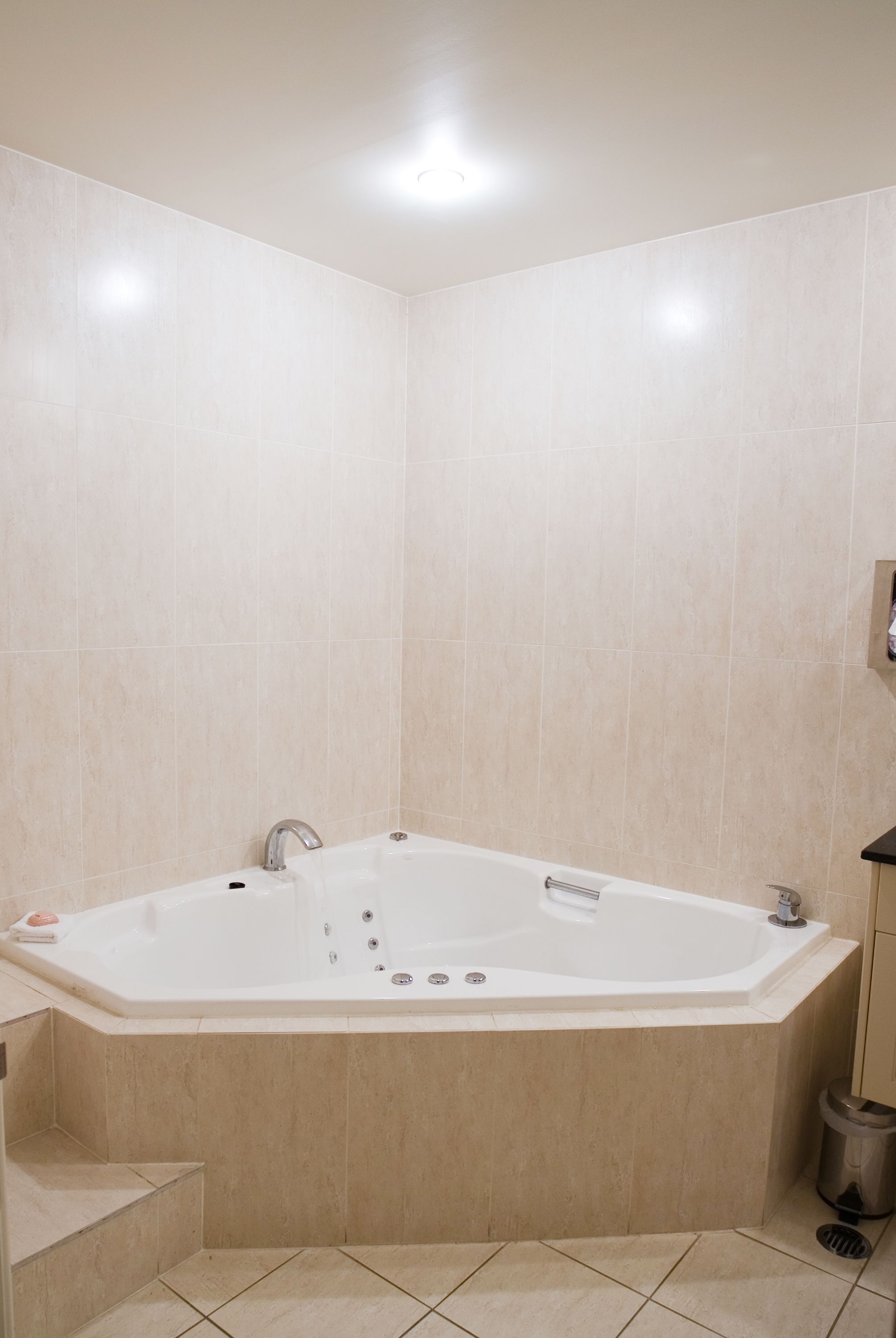 A modern bathroom with a freestanding bathtub, tiled walls, and a small trash bin.