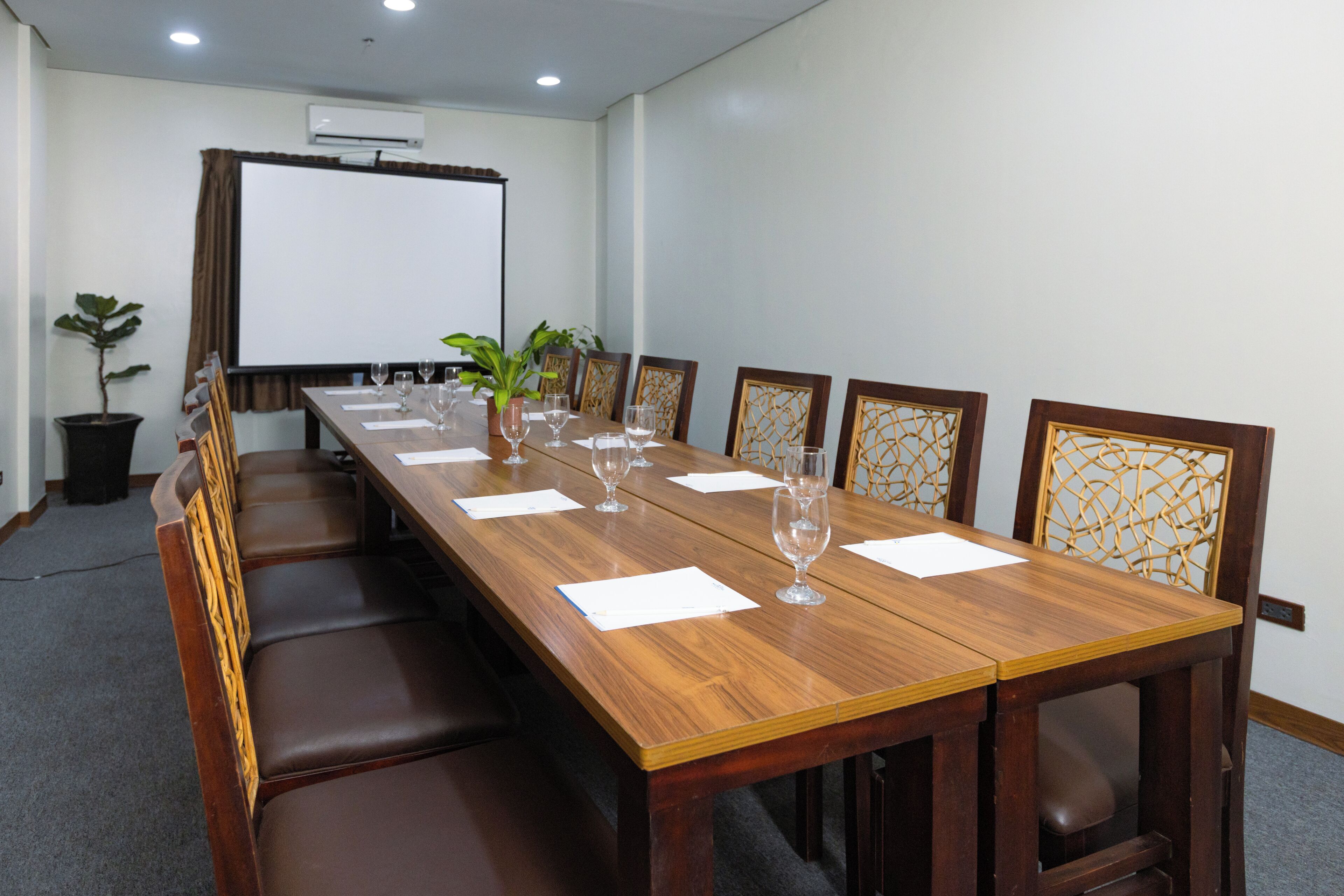 Un salón de conferencias con una larga mesa de madera, seis sillas y una pizarra.
