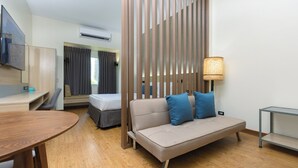 Una habitación de hotel moderna con sofá, escritorio, televisión y lámpara.