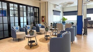 Un vestíbulo moderno con zonas de estar, un mostrador de recepción y ventanas amplias.