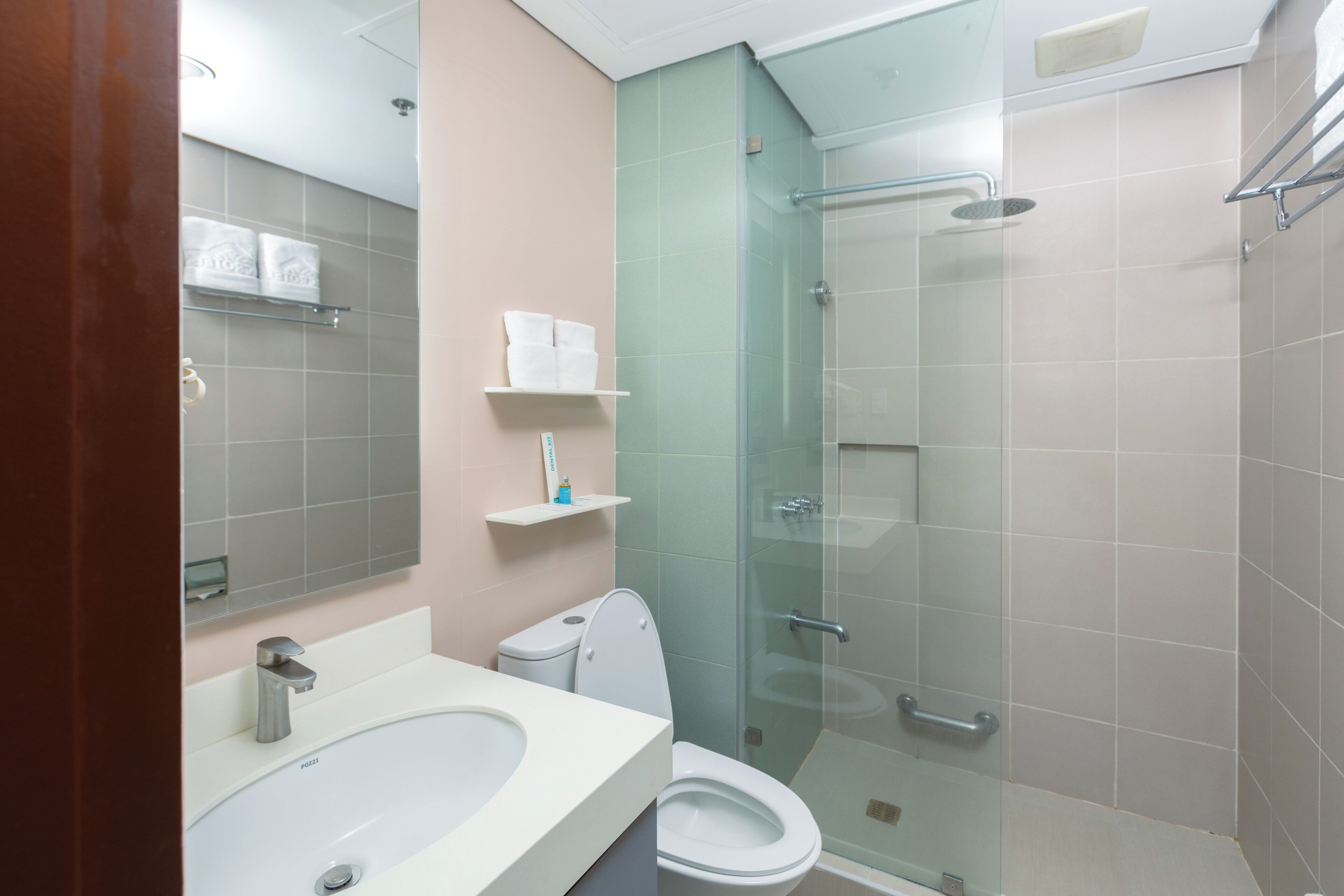A modern bathroom with a white sink, toilet, and glass shower enclosure.