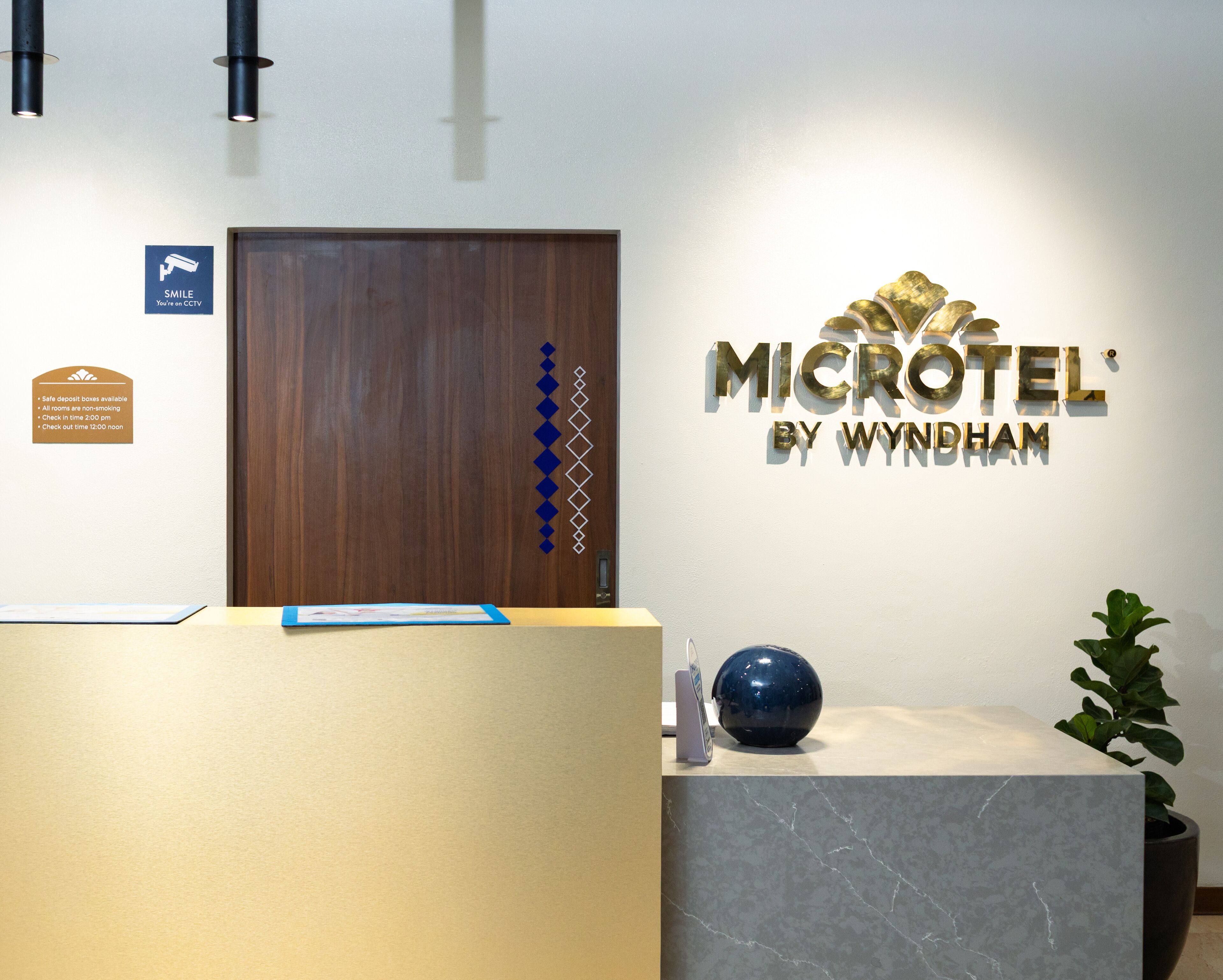A reception desk with a wooden door, a sign for 'MICROTEL' by Wyndham, and a blue vase on the counter.